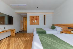XintanHuangshan Tunxi Shangjiexing Riverview Resort Hotel的一间有两张床和一台平板电视的酒店房间