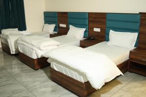 a group of four beds in a room at Hotel Suryo Uday in Dehradun