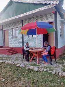 two people sitting at a table with an umbrella at Poddar Retreat in Mal bazar