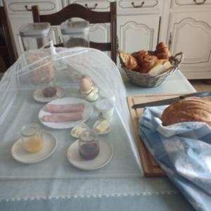a table with a tray of food and a basket of bread at B&B at 3 La Brionniere in Saint-Pierre-du-Chemin