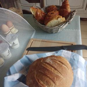 a table with a plate of bread and a basket of croissants at B&B at 3 La Brionniere in Saint-Pierre-du-Chemin +3 photos