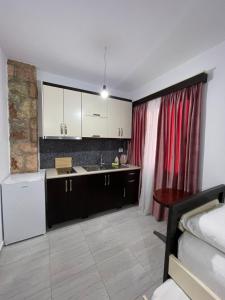 a kitchen with white cabinets and a red curtain at Grand Seaview Apartments in Ksamil