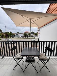 a table and two chairs with an umbrella on a balcony at Studio rénové proche de la plage in Tarnos