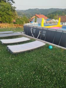 a row of mattresses on the grass next to a pool at Kucica za odmor in Belanovica