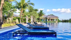 a swimming pool with two lounge chairs in front of a house at Family House Casa Seaside Rayong in Ban Chak Phai