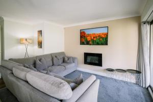 a living room with a couch and a tv at 2 bedroom 2 bathroom luxury apartment 1 minute from Lake pet friendly free parking - FREE off-site Health Club access with Pool, Sauna, Steam Room & Gym Short 10 Minute Drive Away in Winster