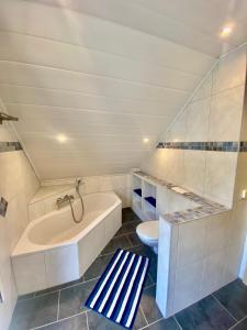 ein weißes Badezimmer mit Badewanne und Toilette in der Unterkunft Ferienhaus am Waldrand Village Holiday home in Bobenheim am Berg + 22 Fotos