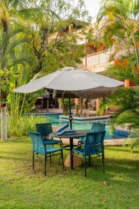 Una mesa y sillas bajo una sombrilla junto a una piscina. en Dayo Hotel, en Flecheiras