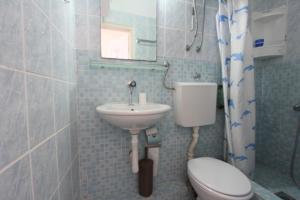 a bathroom with a sink and a toilet and a mirror at Apartman Ksjusa in Sutomore