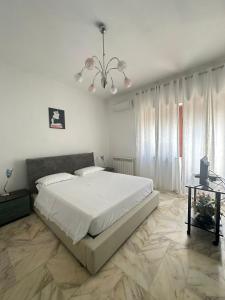 una camera da letto con un grande letto bianco e un lampadario a braccio di Affittacamere Casa Flora a Peschici