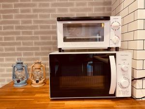 a microwave and a toaster oven sitting on a counter at 波止場の海まで徒歩30秒の貸切宿 "ギョグンミニ" "Gyogun Mini" in Ainan