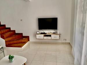 a living room with a television on a white wall at Résidence du Récif - Le Dodo in Bain Boeuf