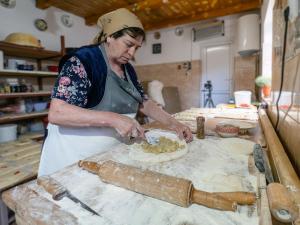 a woman in a kitchen making a pizza at Casa Taraneasca "OM BUN" in Alămor
