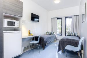 a room with two beds and a table and chairs at Forenom Hostel Vantaa Aviapolis in Vantaa
