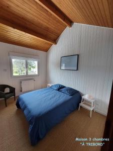 - une chambre avec un grand lit bleu et une télévision dans l'établissement À la vie, à la mer., à Sangatte