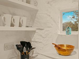 Una cocina con paredes blancas y un cuenco en un estante. en Garth Yr Hebog, en Porthmadog