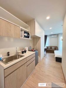 a kitchen with a sink and a living room at อีสต์วิลล์บางแสน36 in Ban Hua Khao Sammuk