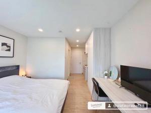a white bedroom with a bed and a television at อีสต์วิลล์บางแสน36 in Ban Hua Khao Sammuk