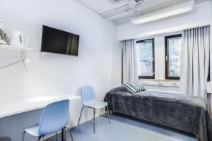 a bedroom with a bed and a television at Forenom Hostel Vantaa Aviapolis in Vantaa