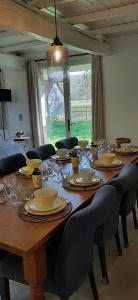 a large wooden table with chairs and glasses on it at La Longère du Clos Saint Martin in Cavron-Saint-Martin