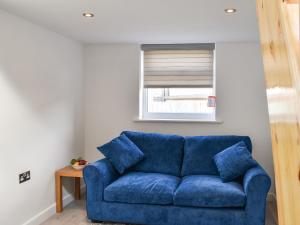 ein blaues Sofa im Wohnzimmer mit Fenster in der Unterkunft The Boat House in Padstow