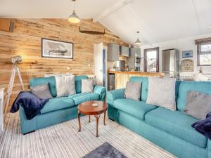 a living room with two blue couches and a table at Green Poplars in Gurnard