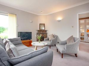 a living room with a couch and chairs and a tv at Leighwood Cottage in Paignton