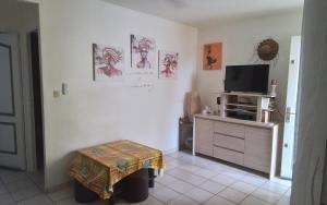 a living room with a tv and a table in a room at Ti case Mellauman : Anse Plage in Les Trois-Îlets
