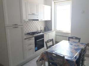 a kitchen with white cabinets and a table with chairs at Casa Regina Elena II in Termoli