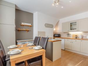 a kitchen with a wooden table and chairs in a kitchen at Rhiw Bank Apartment in Colwyn Bay