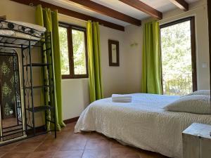 1 dormitorio con cortinas verdes, 1 cama y ventana en Beau mas cévenol avec piscine, en Corbés 27 fotos más