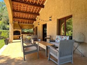 un patio al aire libre con mesa, sillas, mesa y sillón en Beau mas cévenol avec piscine, en Corbés