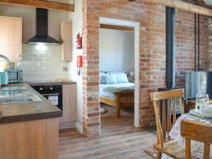 a kitchen with a brick wall and a room with a bed at The Dairy - Uk48756 in Bempton