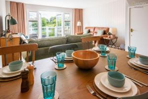 Una sala de estar con una mesa de madera con platos y vasos. en Isis Lakes 31, Bonheur, en South Cerney