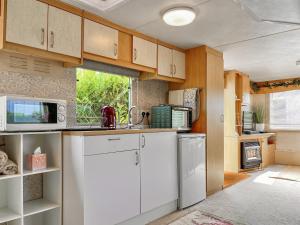 a kitchen with white appliances and wooden cabinets at Goldfinch - Uk48551 in Colchester