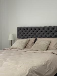 a large bed with a black headboard and pillows at Noa Apartments Pool & Spa in Kragujevac