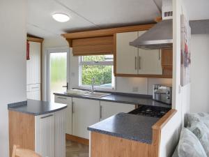 a small kitchen with white cabinets and a sink at Uk47339 - Evergreen in Plumbland