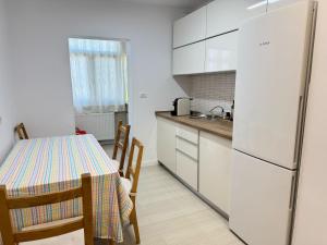 a kitchen with a table with chairs and a refrigerator at Apartament Faleza Nord in Constanţa