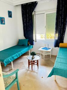 a living room with two beds and a table at Modern 3-Bedroom Apartment in Gated Residence with Pool in Yasmine