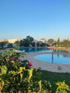 a swimming pool in a park with flowers at Modern 3-Bedroom Apartment in Gated Residence with Pool in Yasmine