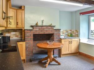 a kitchen with a wooden table in front of a brick fireplace at Uk46833 - Low Hollas Farmhouse in Threlkeld