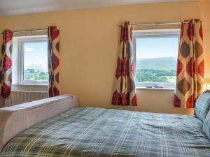 a bedroom with a bed and two windows at Uk46833 - Low Hollas Farmhouse in Threlkeld +15 photos