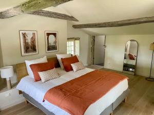 a bedroom with a large bed with orange and white pillows at La Sénéchalerie - Chambres d'hôtes in Chasselay +7 photos