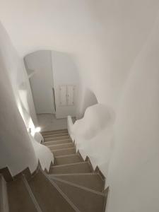 a staircase leading up to a white building with white walls at Santorini White Lotus in Perissa