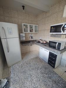 a kitchen with a white refrigerator and a microwave at Apartamento em Cacoal - centro in Cacoal +8 photos