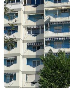 un edificio de apartamentos con ventanas azules y un árbol en Brecani Apartment, en Shëngjin