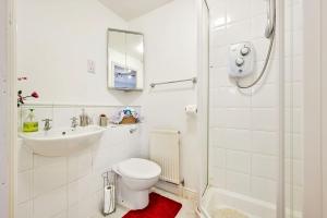 a white bathroom with a toilet and a sink at Riverside Townhouse with Private Garden in London