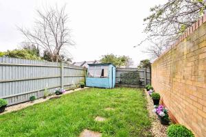 a backyard with a fence and a blue shed at Riverside Townhouse with Private Garden in London