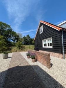 a black house with a brick wall in front of it at Vakantiehuis de Zeeuwse Zonnehoed in Serooskerke