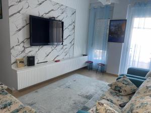 - un salon avec une télévision sur un mur en pierre dans l'établissement Apartament In Lalzi Bay, Lura 1 Complex, à Draç